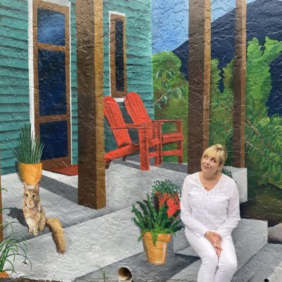 Heidi Pitre sitting in front of a mural of a front porch