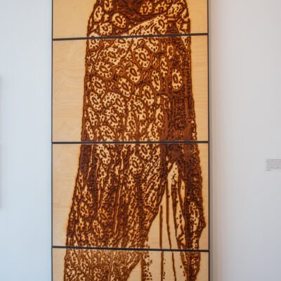 Wood burning of a woman wearing a patterned textile titled Archetype by Lahib Jaddo
