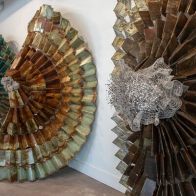 circular sculptures resting on the wall, made from different shades of metal. mesh and circular pieces are seen in the middle.