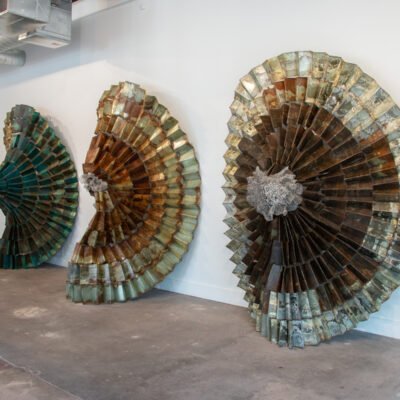 circular sculptures resting on the wall, made from different shades of metal.