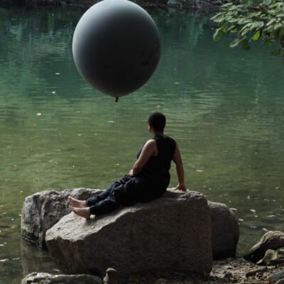 Production still of Ariel René Jackson sitting on a rock holding a balloon, photographed by Hiram Mojica