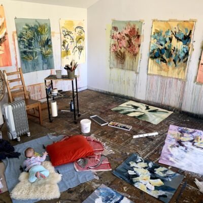 photograph of Caroline Wright's Studio with works in process on the walls and floor, and her baby on a blanket with her