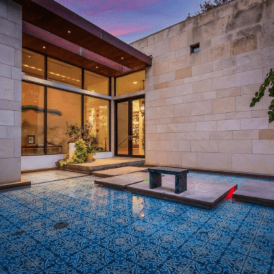 photograph of a pool with colorful patterned tile outside of a modern house