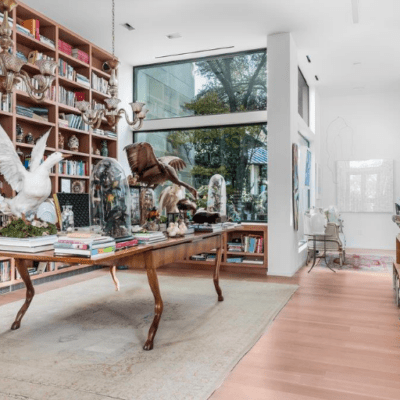 a stylish room with a wall of books and a table with taxidermy birds inside of a house