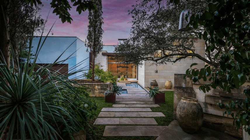 stone pathway surrounded by trees and plants leading to a modern house