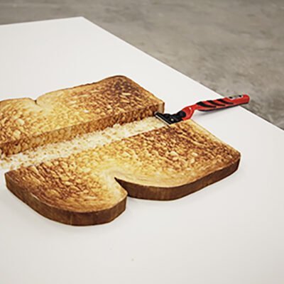 a piece of toast cut down the middle by a red shaving razor titled Daydreaming by Ling-in Ku