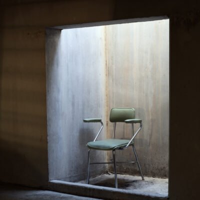 green metal chair sitting in a lit corner.