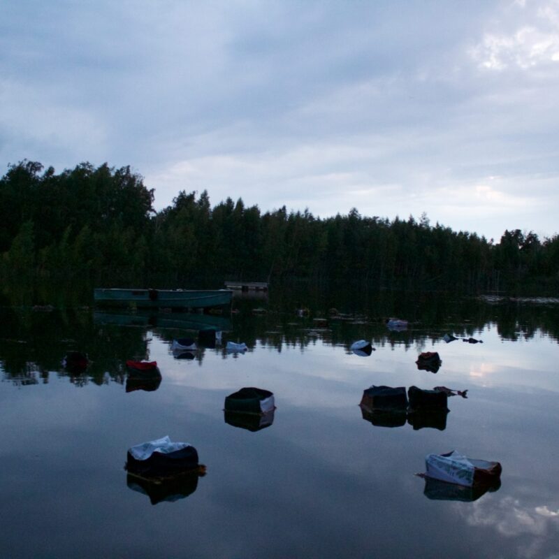 Brianna McIntyre, Parable of the Hidden Maiden, 2017, Site-specific installation photography of a lake with pods made from discarded clothing, pine, and wire floating in the water