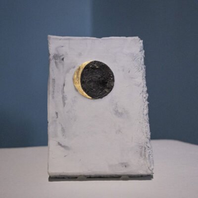 small painting of a gold crescent moon on a white, plaster background