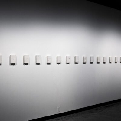 gallery view of 25 rectangular sculptures on the wall