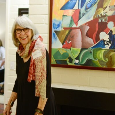 photo of a woman smiling next to a painting