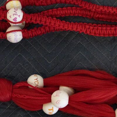 red macrame with beads tied into it.