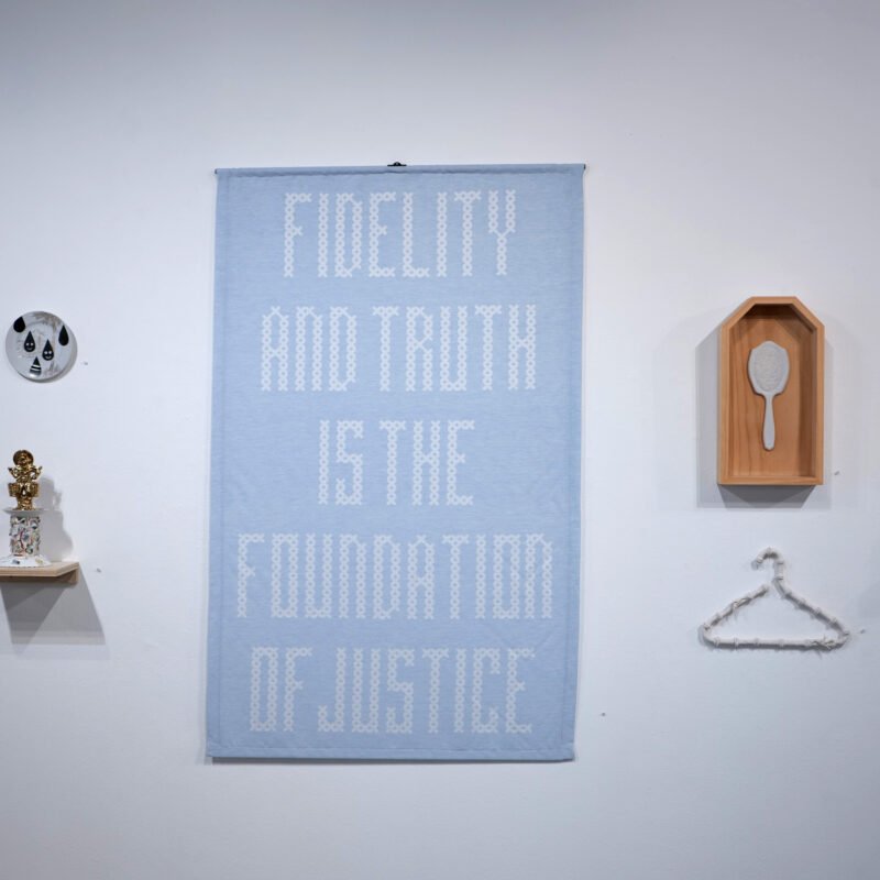 Jennifer Ling Datchuk, Objects of Womanhood (installation view) hanging sign that reads, "fidelity and truth is the foundation of justice."