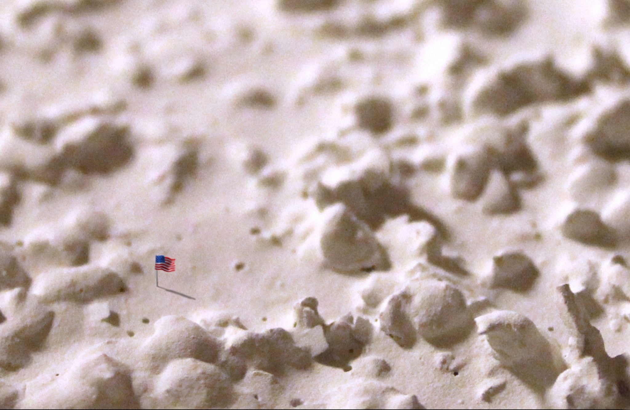 Emily Fleisher, "New Horizons, Bunkbed: Flag"; Digital photograph of clay flag on popcorn ceiling; 10" x 7"